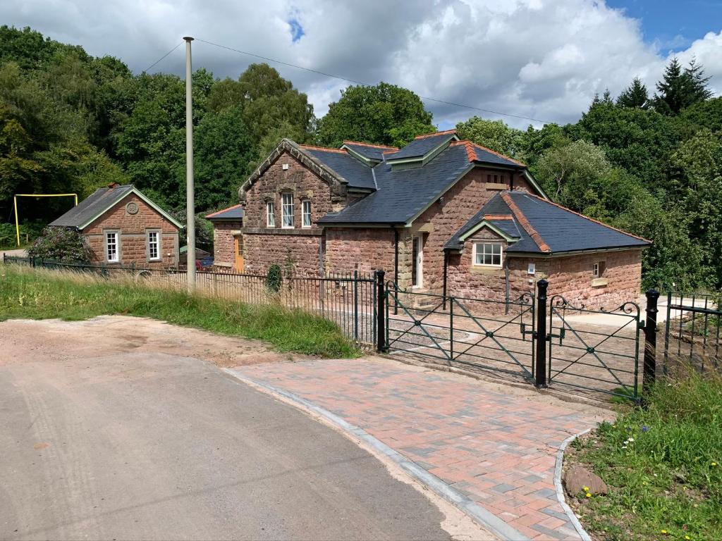 uma casa na berma de uma estrada com um portão em Pumping Station Holidays em Cinderford