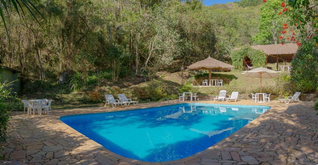 伊比烏納的住宿－Pousada Passaredo Montanha，一个带桌椅和遮阳伞的游泳池