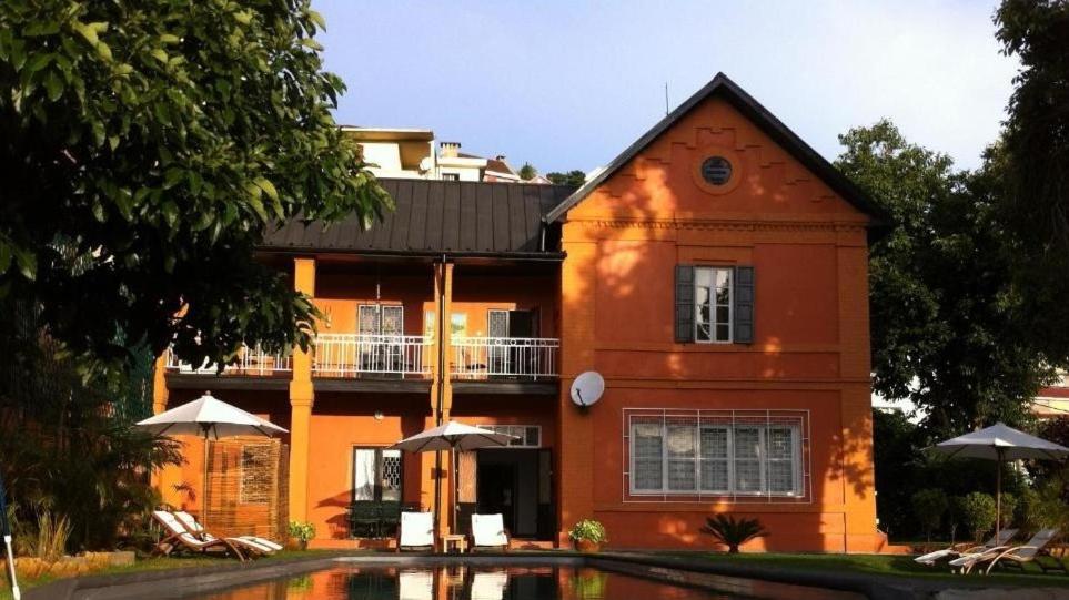 un grande edificio arancione con una piscina di fronte di Maison d'Hôtes Mandrosoa a Antananarivo