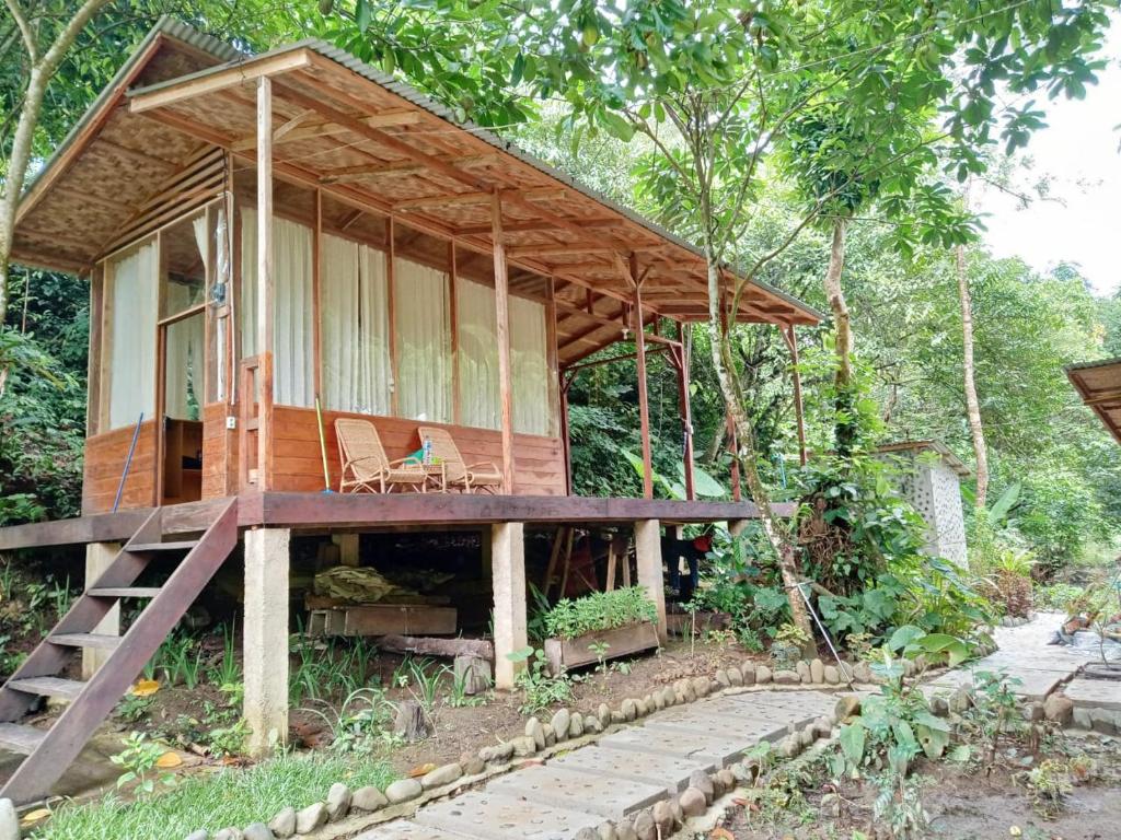 una casa de madera con porche y silla en Bua Guesthouse Tangkahan, en Tangkahan