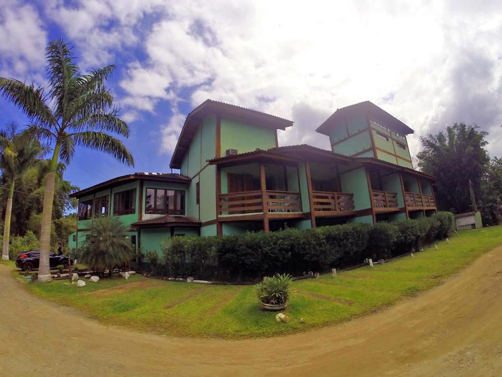 a large house with a palm tree in front of it at Recanto Verde Praia Hotel Juquehy in Juquei