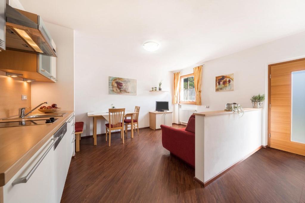 a kitchen and a living room with a red couch at Tischlerhof - Typ C in Tirolo