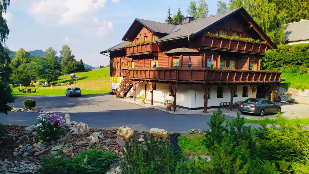 a large wooden house with cars parked in front of it at Pension Grizzly in Ludvíkov