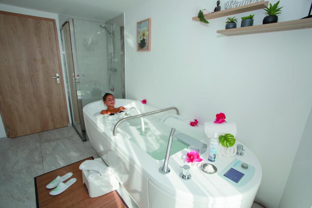 a woman laying in a bath tub in a bathroom at Cristal Hôtel & Spa in Cannes