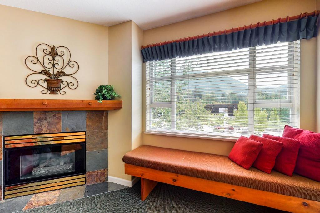 a living room with a fireplace and a red bench in front of a window at Marketplace Lodge in Whistler
