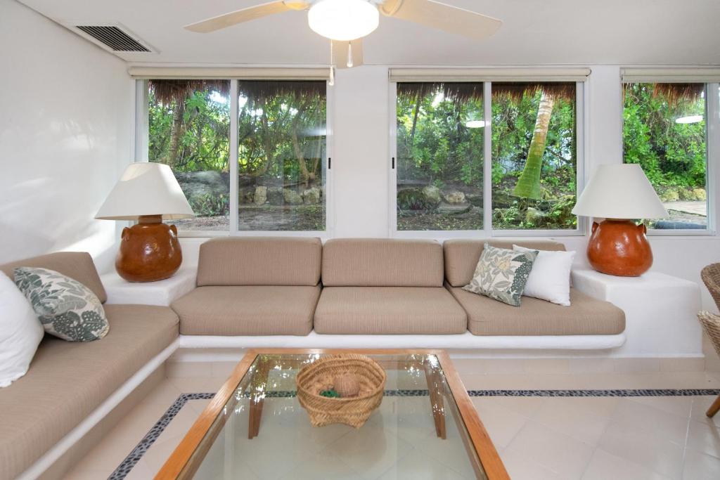 a living room with a couch and a glass table at Las Villas Akumal in Akumal