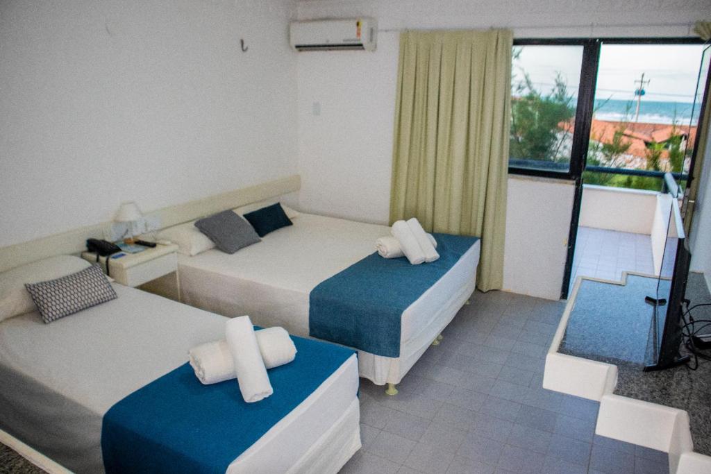a hotel room with two beds and a balcony at Hotel Amarração in Luis Correia