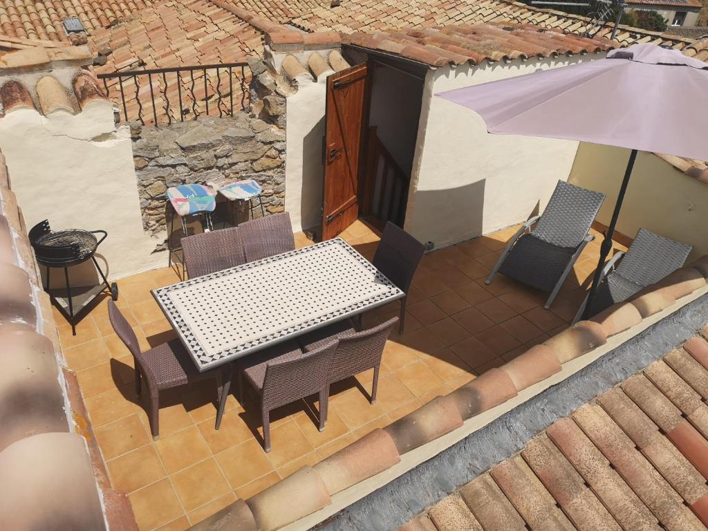 uma mesa e cadeiras e um guarda-sol num pátio em L'apartement deluxe em Azille