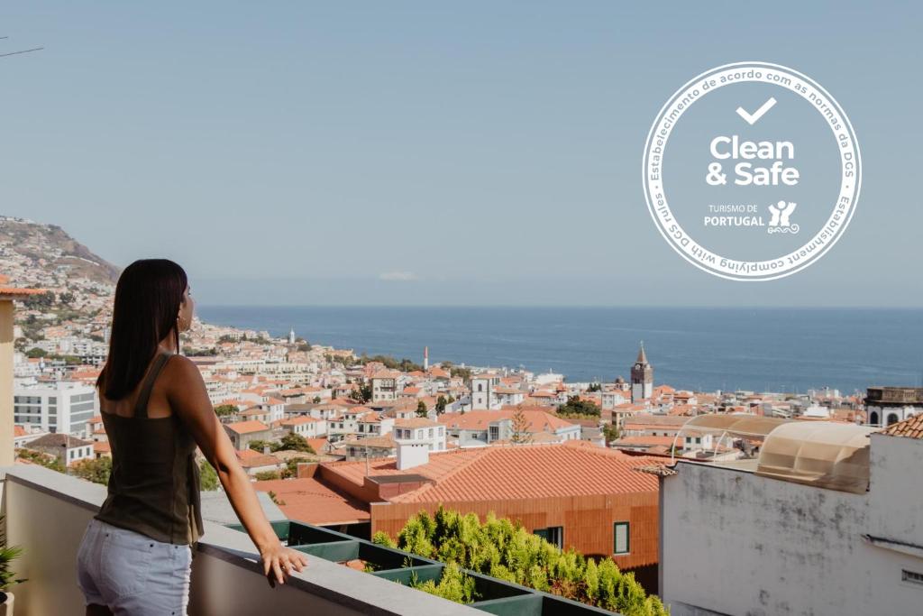 een vrouw op een balkon met uitzicht op een stad bij Colina Mar in Funchal