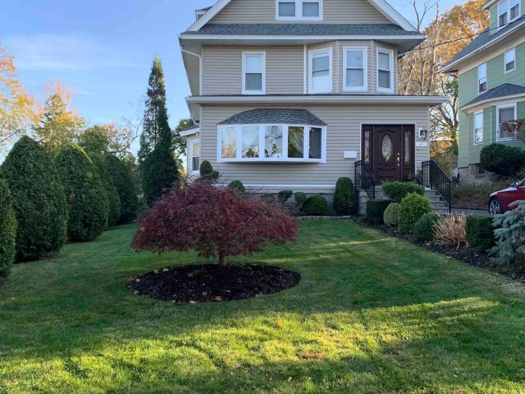 a house with a tree in the middle of a yard at Historical Neighborhood Home in New Rochelle