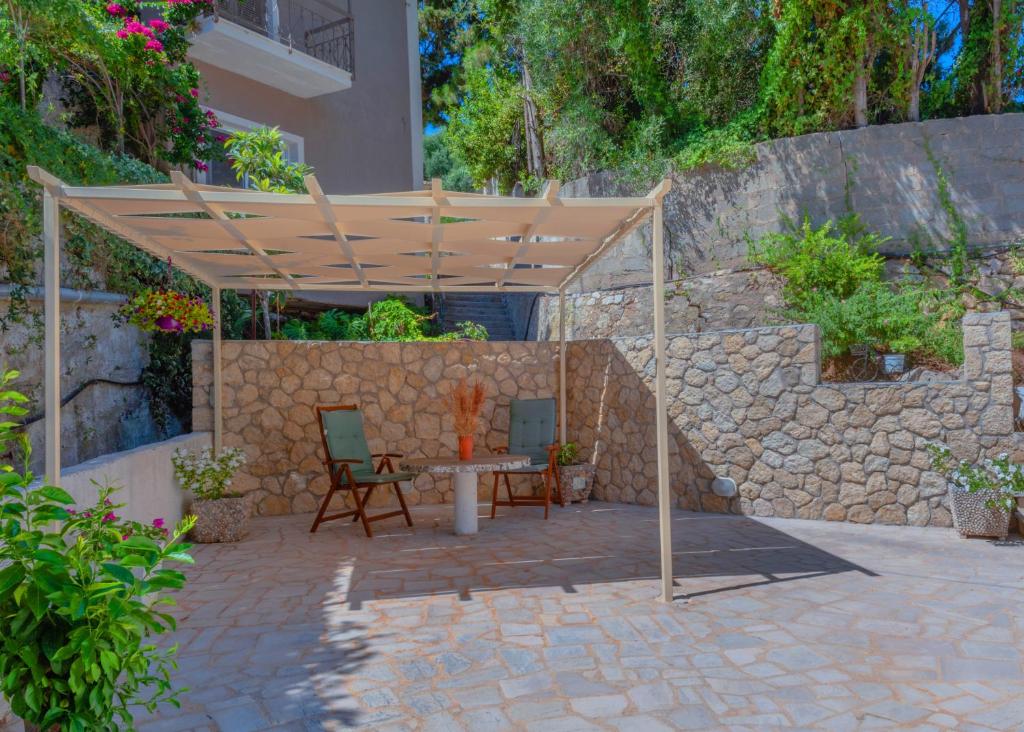 un pergolato in legno con tavolo e sedie su un patio di Villa Mikalef a Perama