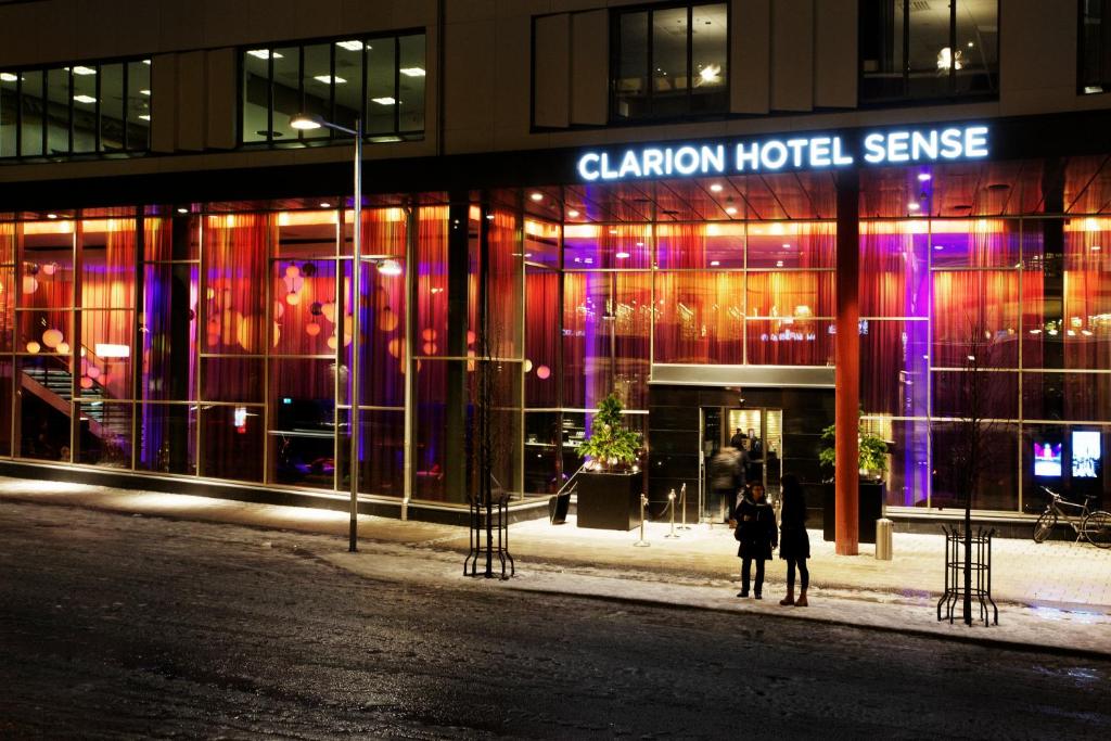 dos personas de pie delante de un edificio por la noche en Clarion Hotel Sense, en Luleå