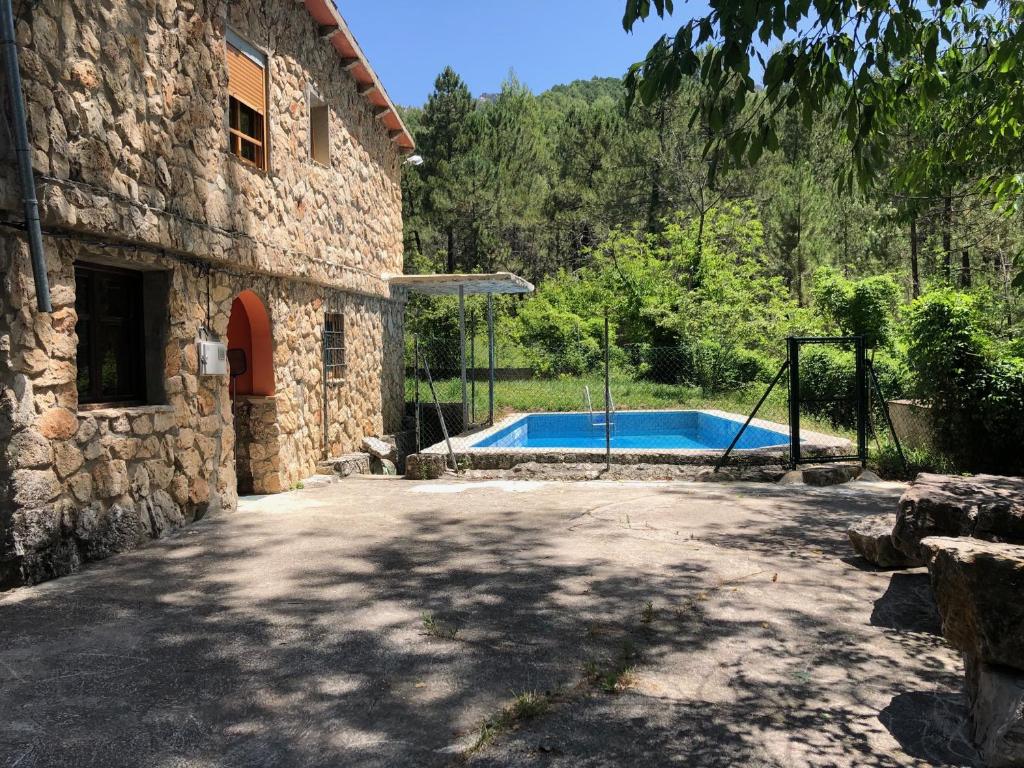 une maison en pierre avec une piscine dans une cour dans l'établissement Casas Rurales Arroyo de la Sierra, à Yeste