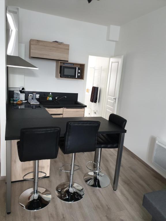 a kitchen with a black table and four bar stools at Au 16 in Dijon