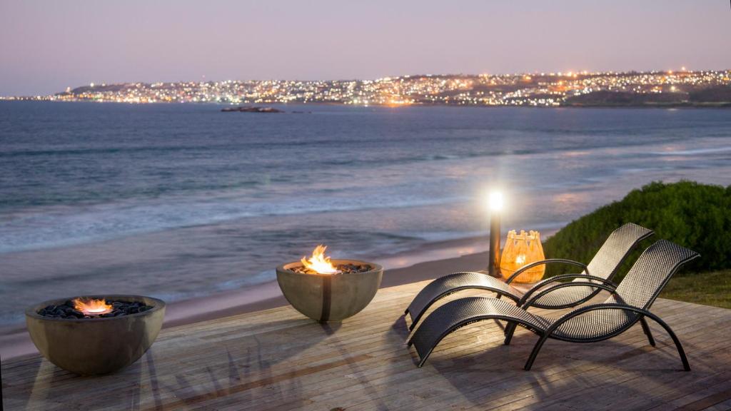 Mossel Bay的住宿－非洲海洋莊園酒店，海滩上晚上有两张火的桌子