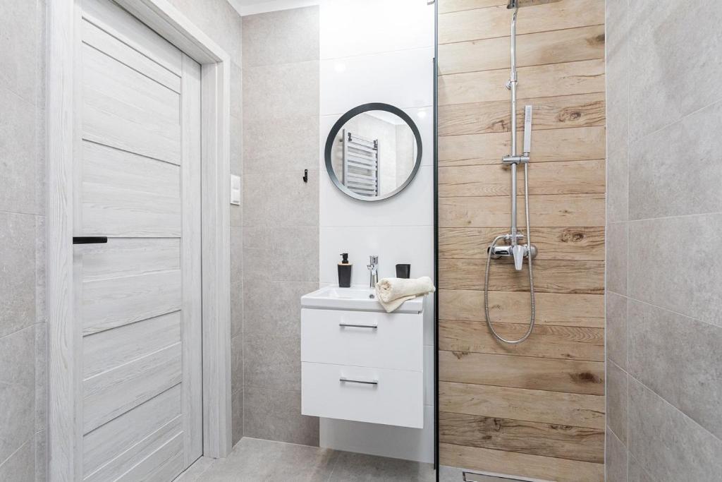 a bathroom with a shower and a sink and a mirror at Rybacka 48 - Twoje miejsce wypoczynku, domki, pokoje, apartamenty in Jantar