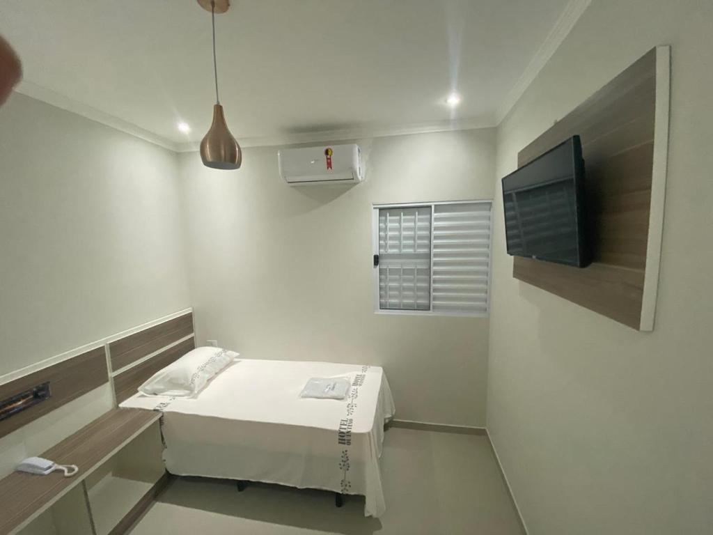 een kleine witte kamer met een bed en een televisie bij Hotel Quintino in Sao Paulo