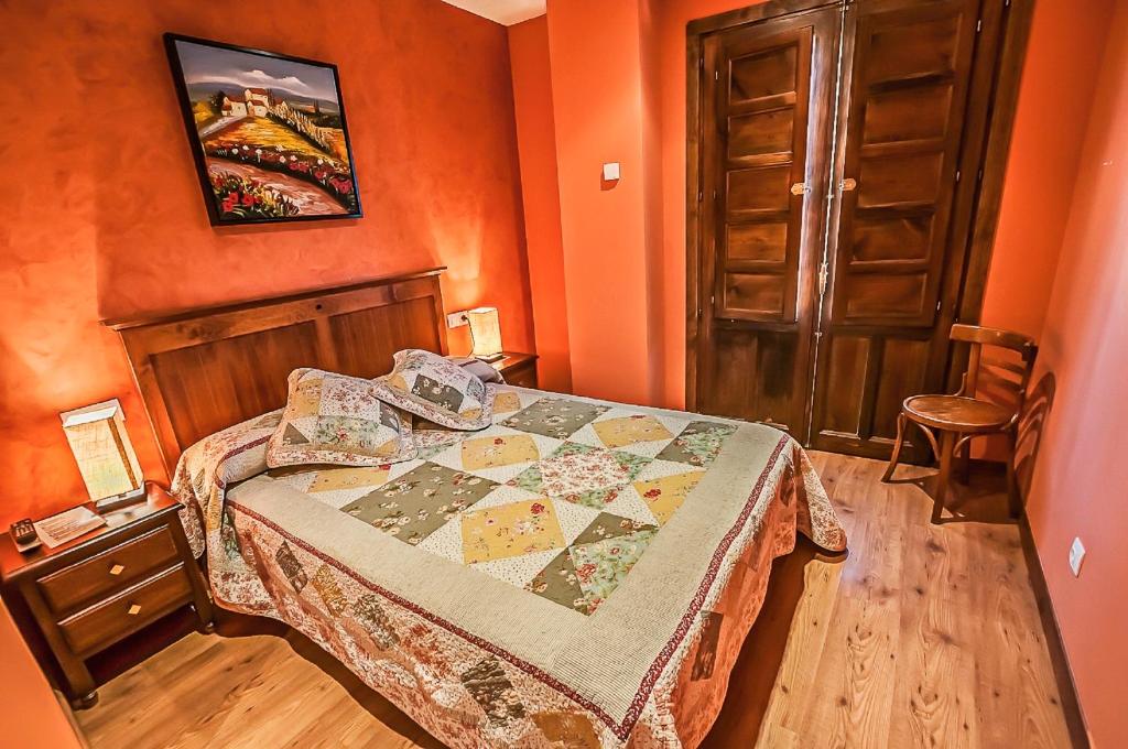 a bedroom with a bed in an orange room at Hotel Rural Pajarapinta in Molinaseca