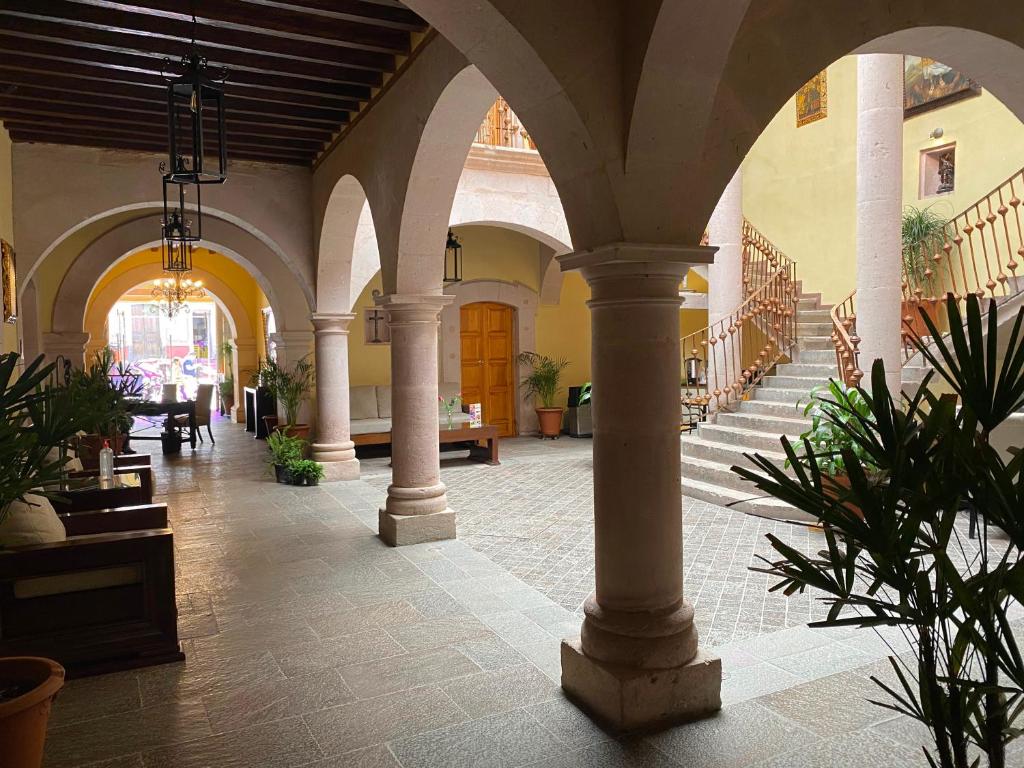 un edificio con columnas y un pasillo con plantas en Hotel Casa Faroles Centro Histórico en Zacatecas