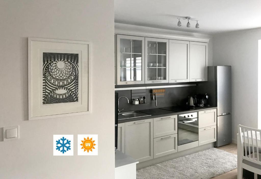 cocina con armarios blancos y nevera de acero inoxidable en Apartament Flora Deluxe Naświetlanie UV, en Białystok