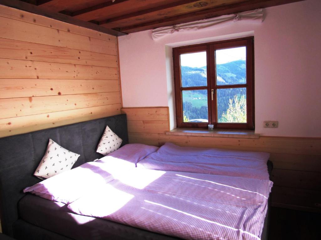 Bett in einem Zimmer mit Fenster in der Unterkunft Bio Bauernhof Brandgut in Mühlbach am Hochkönig