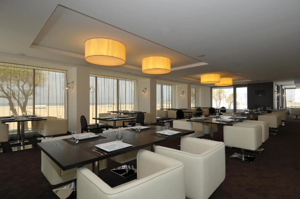 - une salle à manger avec des tables, des chaises et des fenêtres dans l'établissement Sweet Atlantic Hotel & Spa, à Figueira da Foz