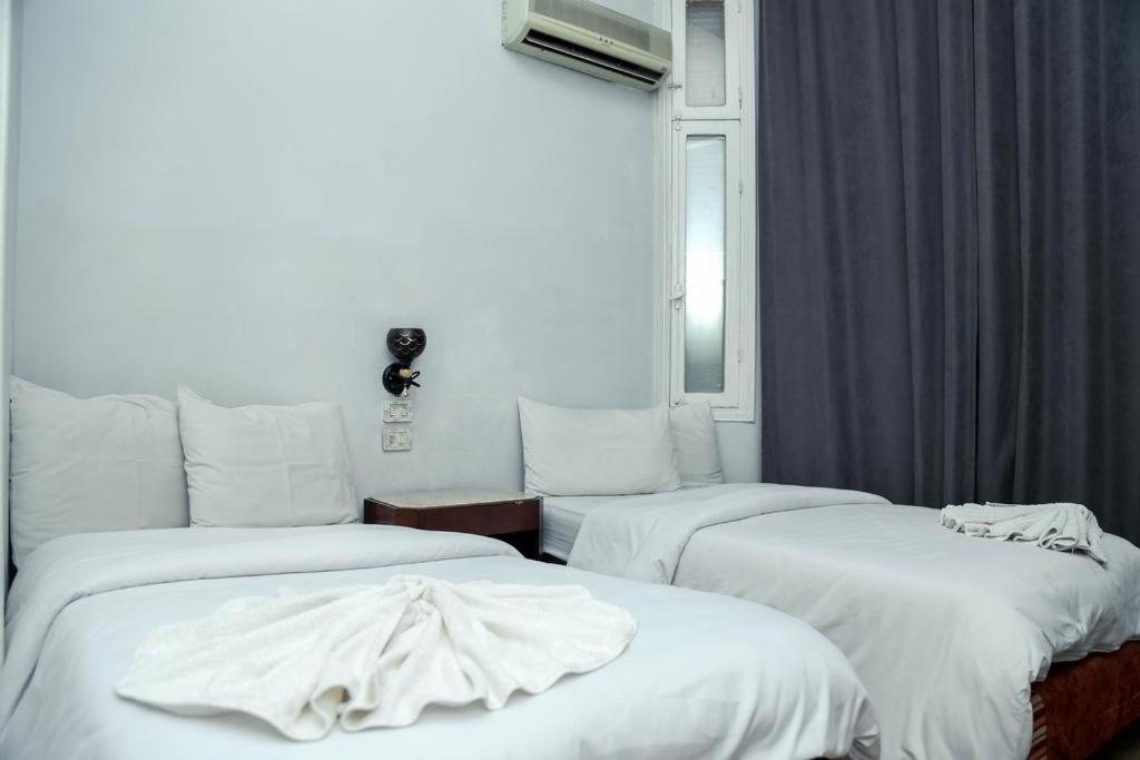 Habitación con 3 camas y sábanas blancas. en My Hotel en El Cairo