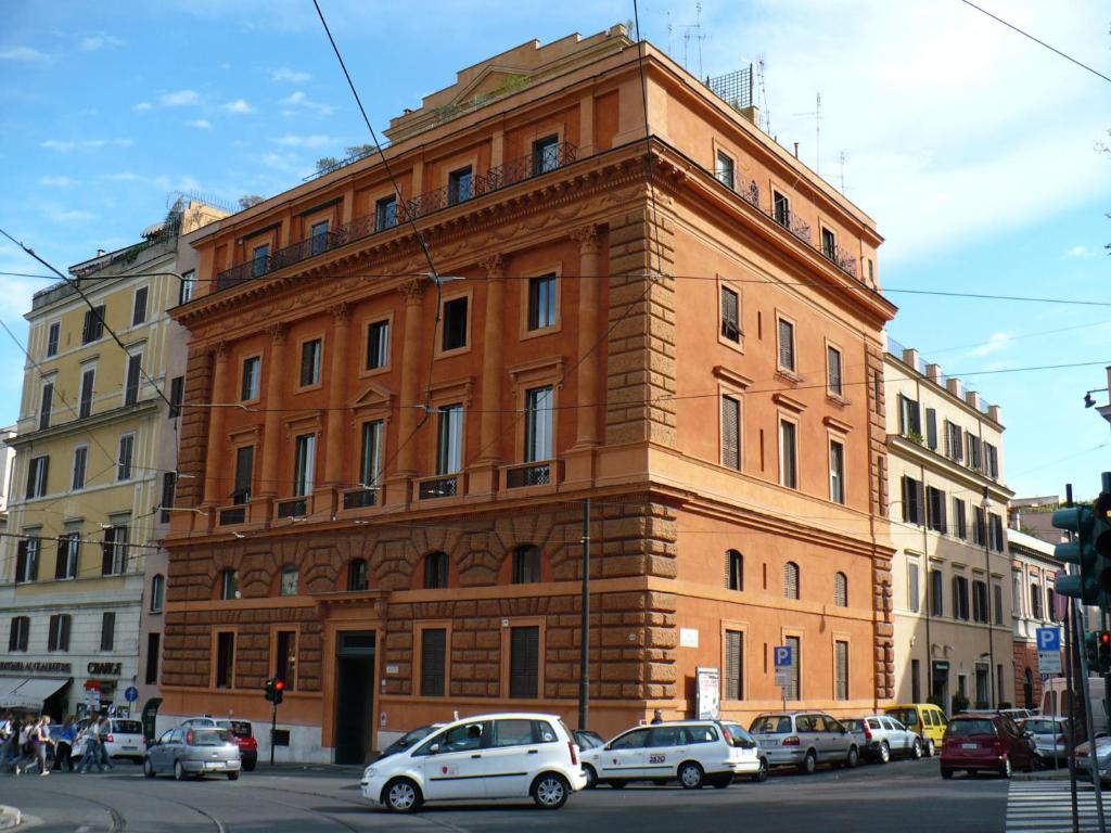 un grand bâtiment en briques avec des voitures garées devant lui dans l'établissement Casa Vacanze Colosseo da Fernando no elevator, à Rome