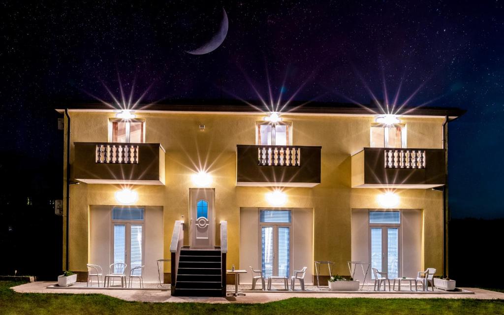 a building with tables and chairs in front of it at night at Guesthouse Palombaro in Umag