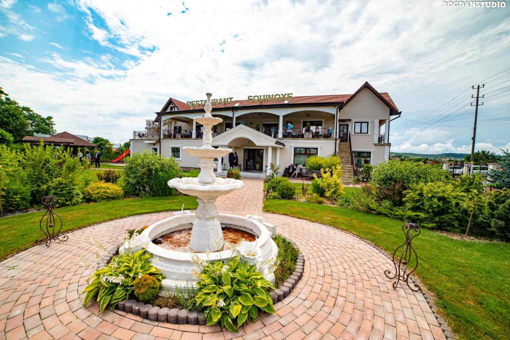 a fountain in front of a house with a building at Equinoxe Royal Reghin in Reghin