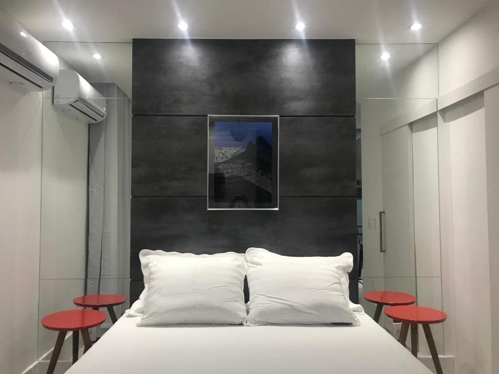 1 dormitorio con cama blanca y taburetes rojos en Ipanema Prudente Studio, en Río de Janeiro