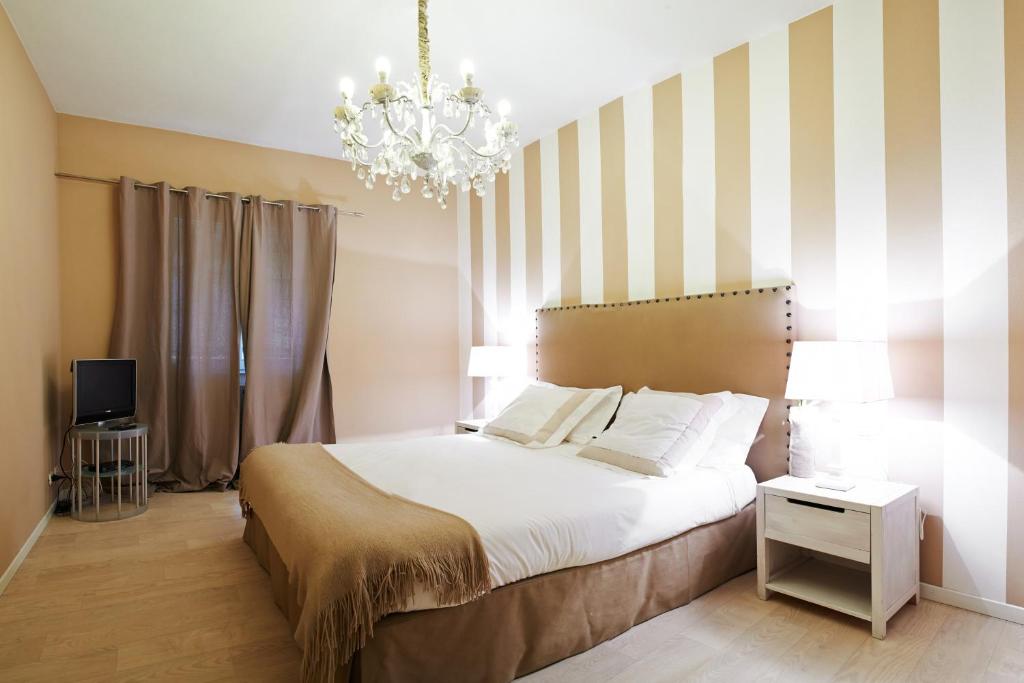 sypialnia z dużym łóżkiem i żyrandolem w obiekcie Petite Suite w Bergamo