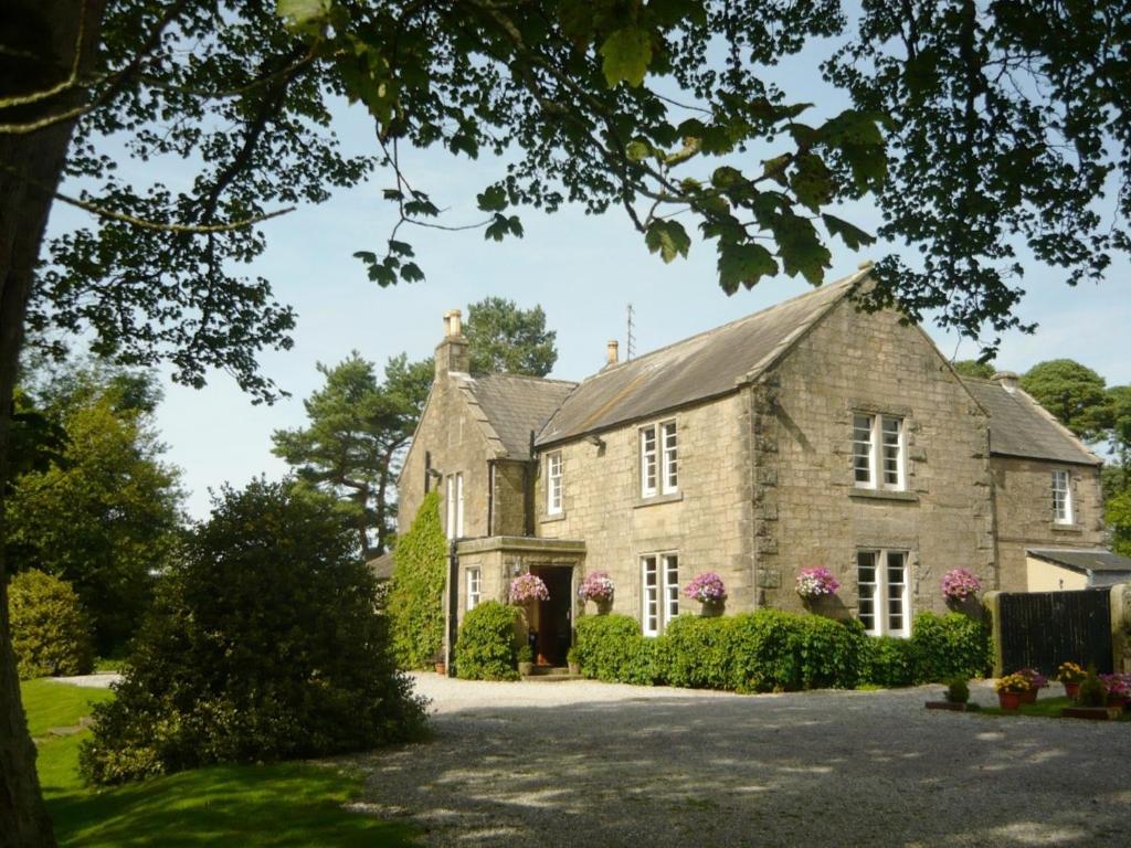 a large stone house with a driveway at Blackaddie House Hotel in Sanquhar