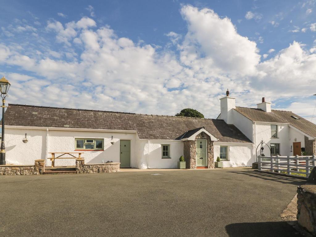 ein weißes Gebäude mit einem Tor und einer Straße in der Unterkunft Buarthau Cottage in Caernarfon