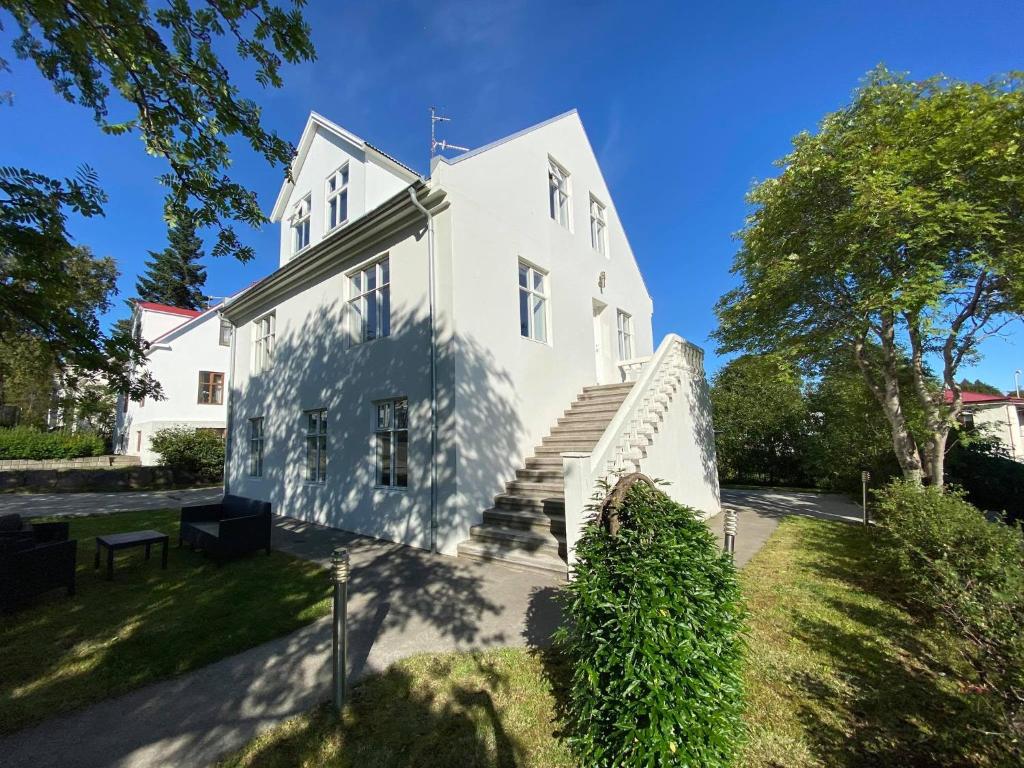 Une grande maison blanche avec des escaliers et des arbres dans l'établissement Akureyri Central House, à Akureyri