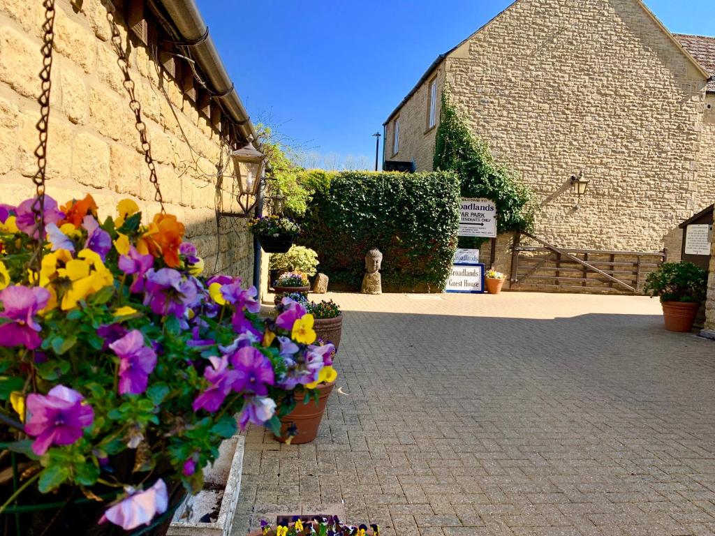 a bunch of flowers in pots next to a building at Broadlands in Bourton on the Water