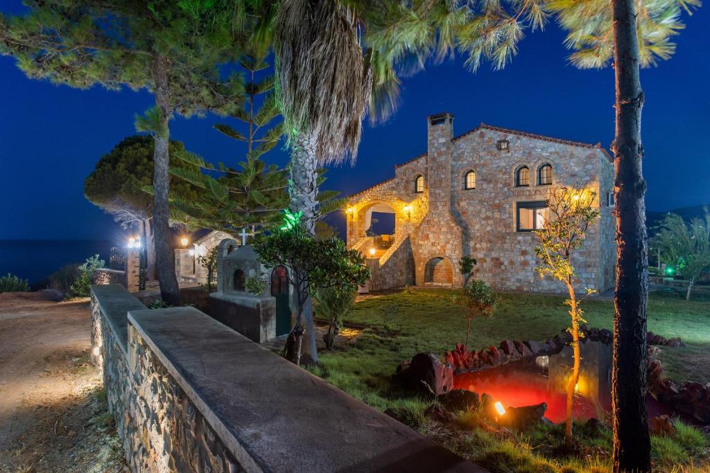 an old stone house with palm trees at night at VILLA AVLOS in Monemvasia