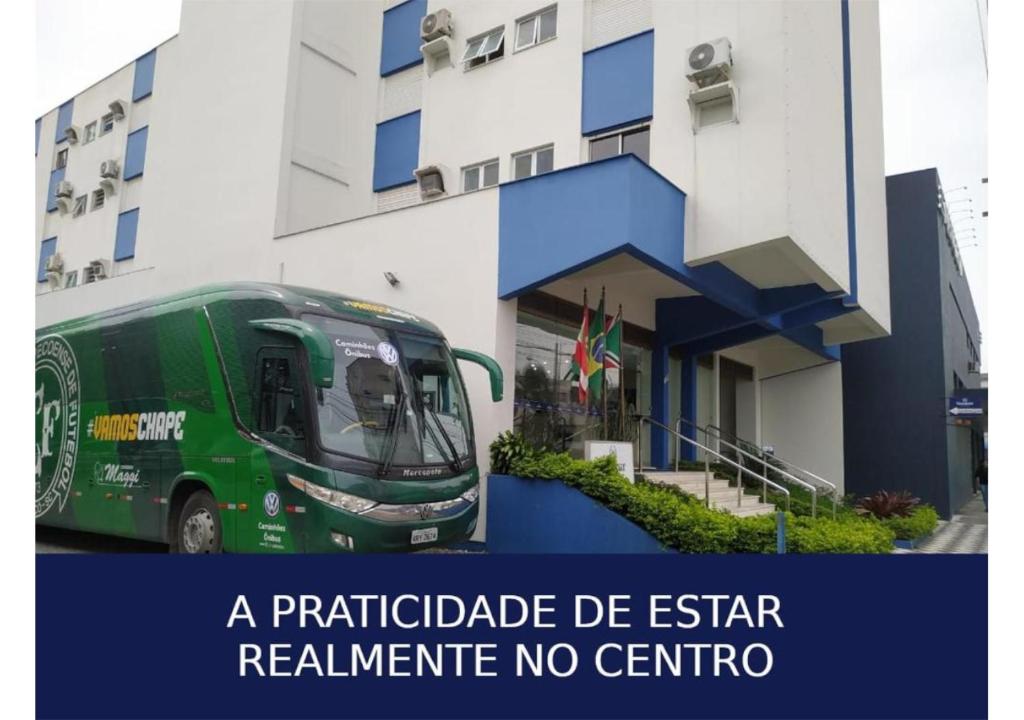 a green bus parked in front of a building at Soratur Hotel & Coworking in Criciúma