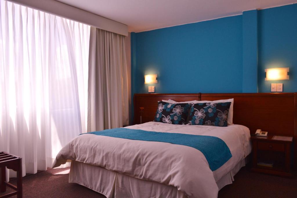 a bedroom with blue walls and a bed with pillows at La Carolina Inn in Quito