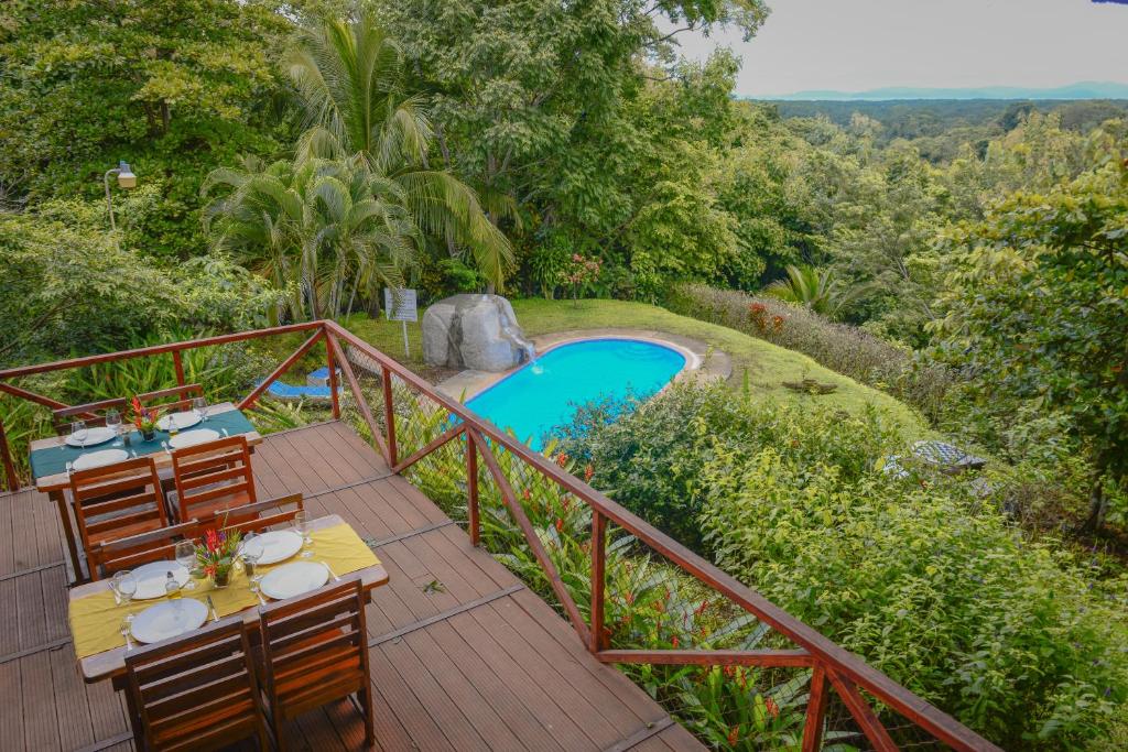 a deck with a table and chairs next to a pool at Hotel Cerro Lodge in Tarcoles