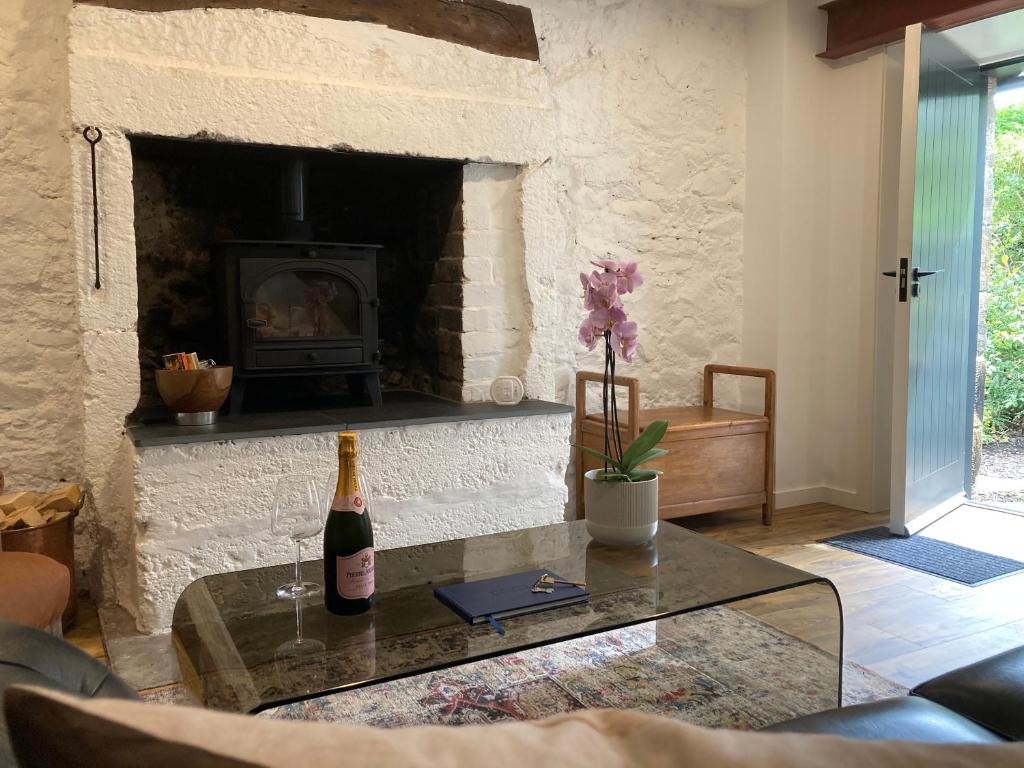 a living room with a fireplace with a bottle of wine on a table at Beautifully Renovated Self-Contained Farm Cottage - close to beaches, North Berwick and the Golf Coast in North Berwick