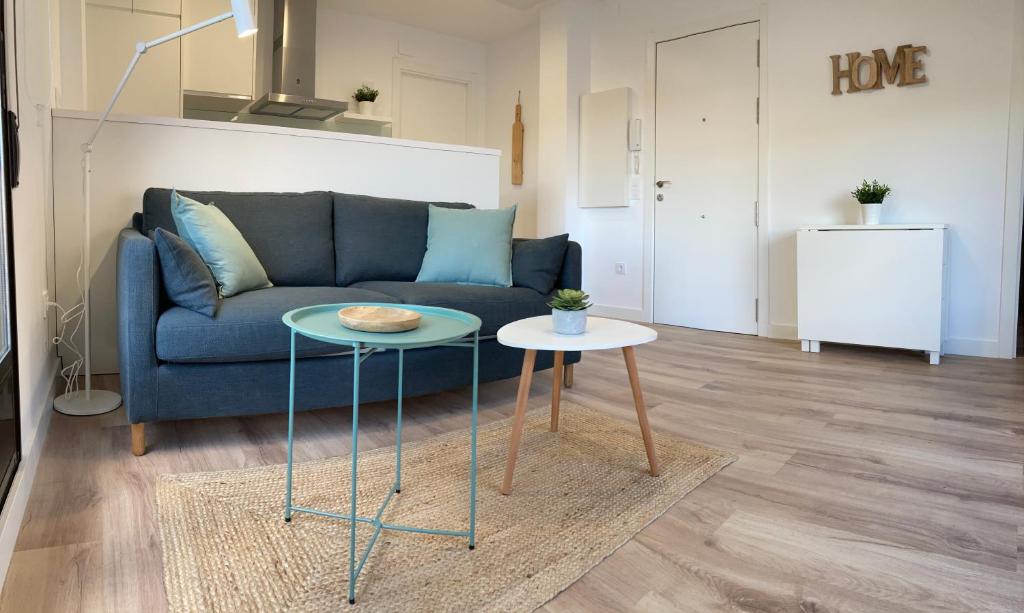 uma sala de estar com um sofá azul e duas mesas em TeruelHOME I Con Encanto y parking em Teruel
