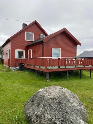 uma grande rocha em frente a uma casa vermelha em Bestemorhuset em Kariel