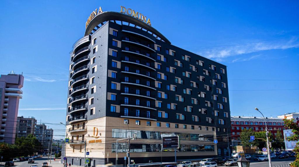 ノヴォシビルスクにあるDomina Hotel Novosibirskの看板が上がる高層ビル