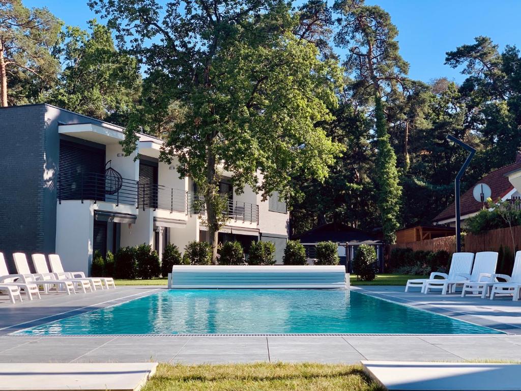 a swimming pool with white chairs and a building at Dom FANØ Baltic 3 - Aprent in Pobierowo