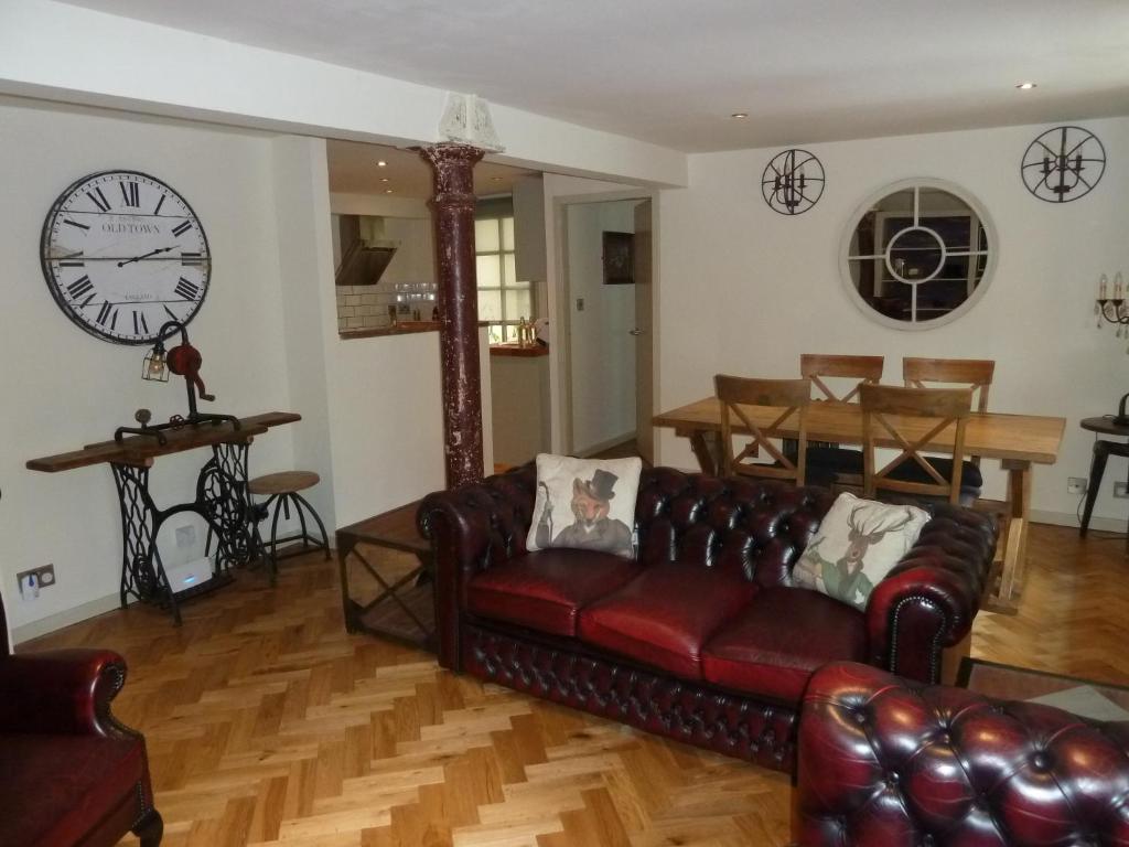 a living room with a couch and a clock on the wall at Old town Brewery Apartment in Edinburgh