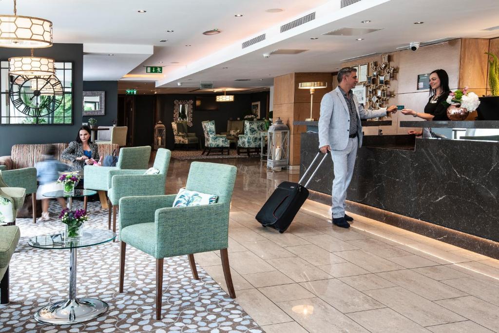 a man with a suitcase in a hotel lobby at The Address Citywest (formerly Kingswood Hotel) in Citywest