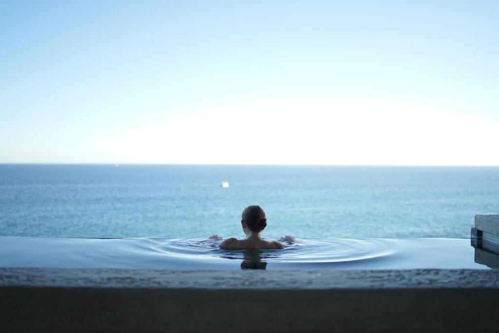 une personne assise dans une piscine donnant sur l'océan dans l'établissement Mayflower Hotel Malta, à San Pawl il-Baħar