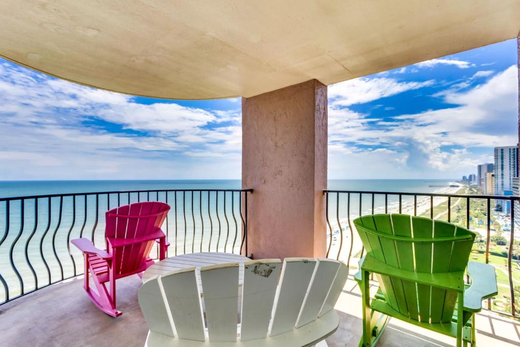 a balcony with colorful chairs and a view of the ocean at Hosteeva Palms Resort 3BR 15th Floor Oceanfront in Myrtle Beach