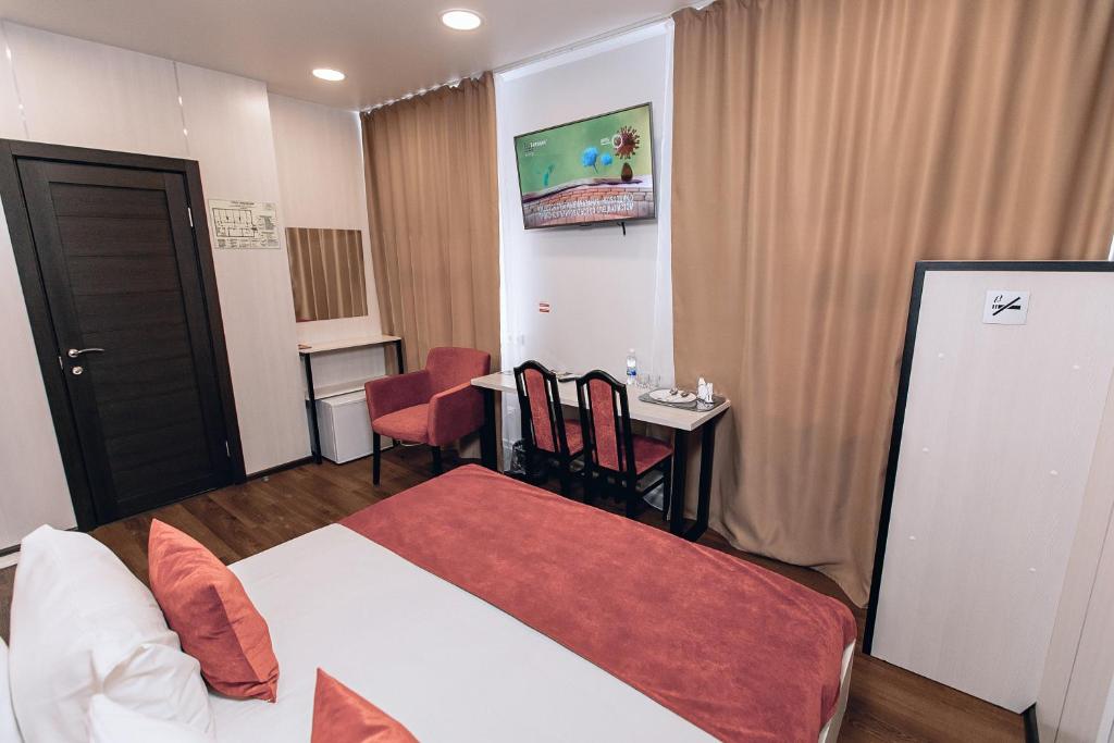 バルナウルにあるRedFox Hotelのベッドとテーブルが備わるホテルルームです。